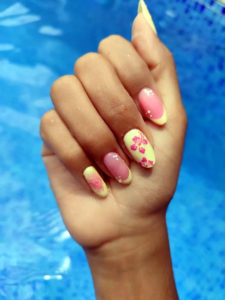 Uñas almendradas amarillo pastel y rosa con hibiscos rosa pintados a mano y puntos blancos