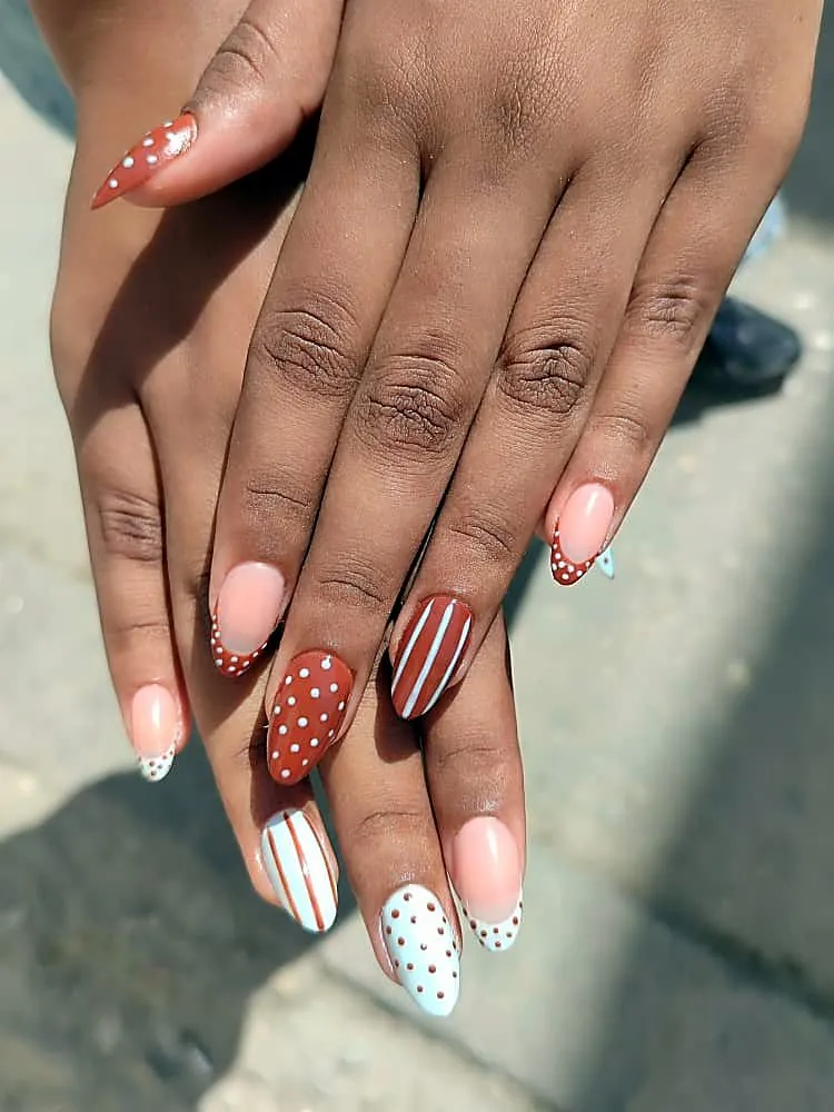 Uñas almendradas en terracota y azul claro con lunares, rayas y francesas de puntos