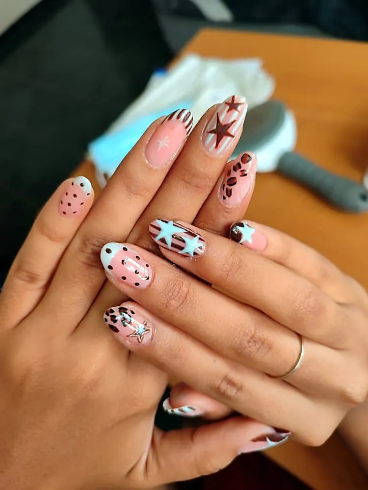Uñas almendradas rosa con estrellas azul claro, rayas y estampado de leopardo marrón
