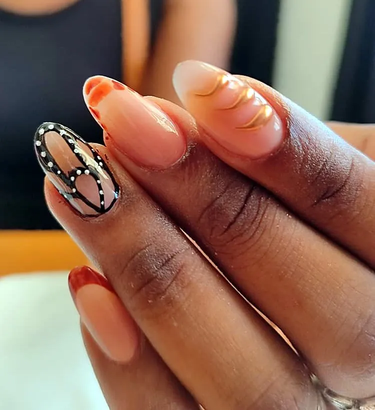 Uñas almendradas nude con un ala de mariposa negra con puntos blancos, líneas doradas y francesa terracota