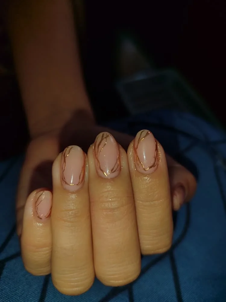 Uñas almendradas nude con francesa dorada y detalles brillantes