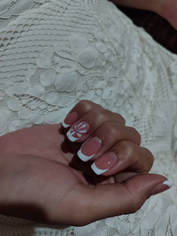 Uñas almendradas nude con puntas blancas sobre tela bordada